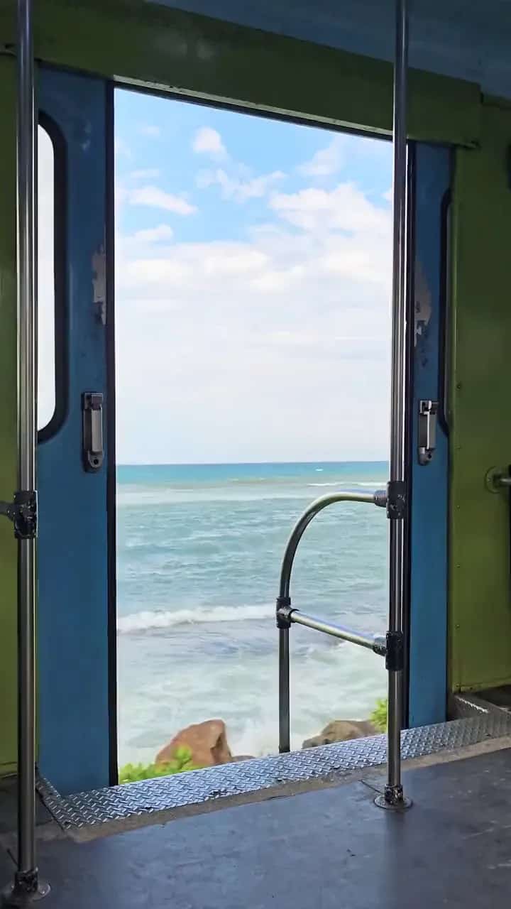 View of the sea from the open door of a coastal train